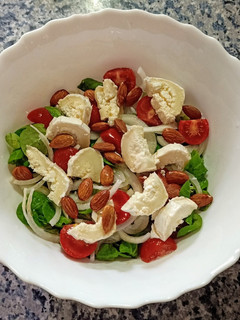 Una foto de Ensalada de canónigos, Rulo de cabra, cherry y almendras