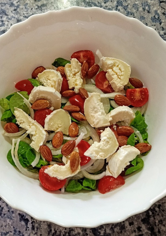 Una foto de Ensalada de canónigos, Rulo de cabra, cherry y almendras