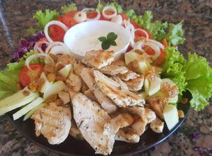 Una foto de Pollo, ensalada colorida y aderezo yogurt