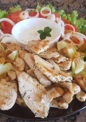 Una foto de Pollo, ensalada colorida y aderezo yogurt