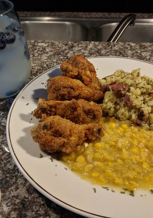 A picture of Fried honey 🍊 chicken drummetes and parsley potatoes with corn.