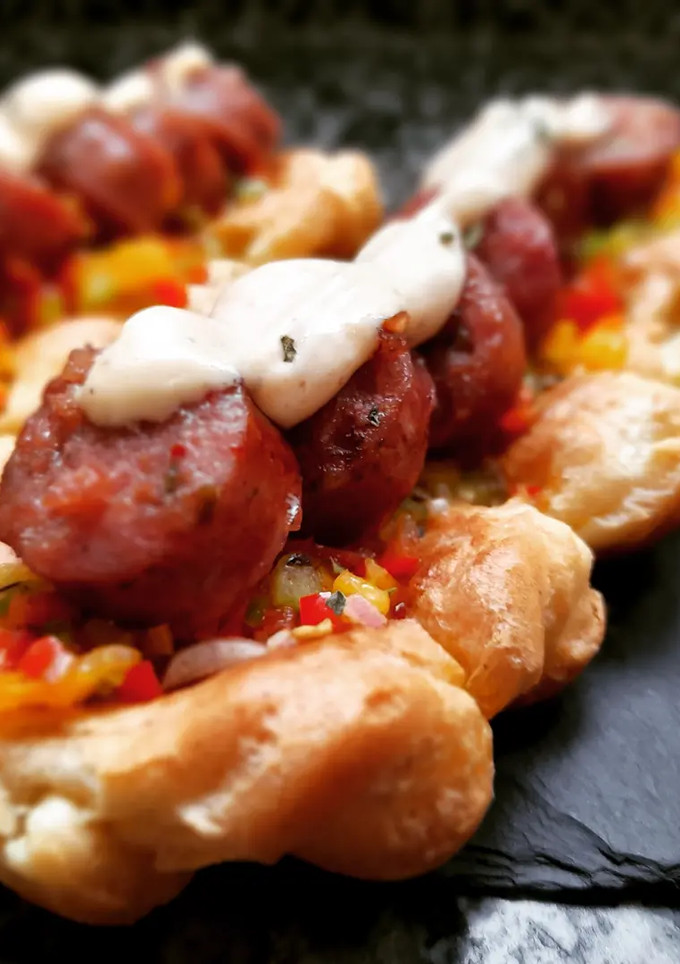 Una foto de Choripan con salsa criolla en base de masa choux