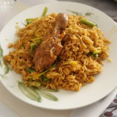 A picture of Jollof rice with spring onion and chicken.