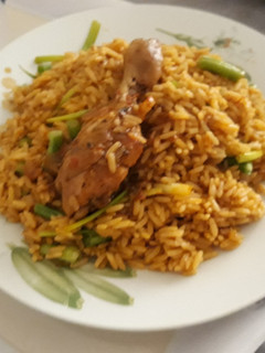 A picture of Jollof rice with spring onion and chicken.