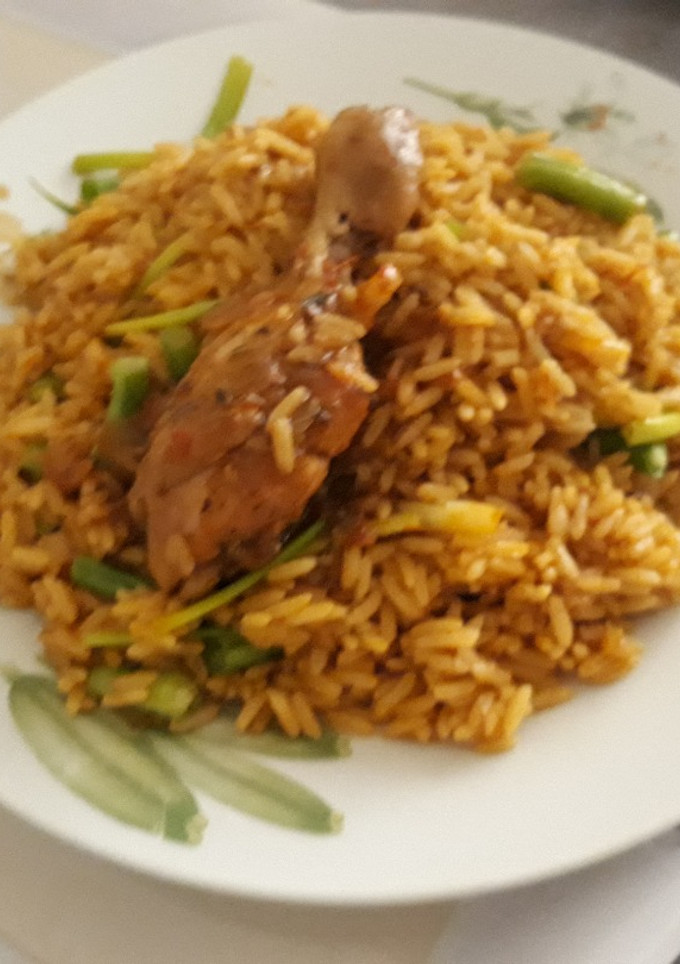 A picture of Jollof rice with spring onion and chicken.