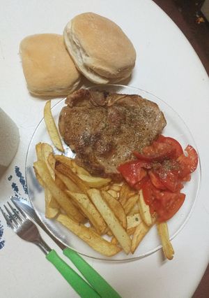 Una foto de Chuleta de cerdo con papas fritas y ensalada de tomate