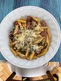 Penne rigatti con hongos portobello, salchicha parrillera y cebolla de verdeo