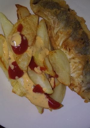 A picture of Fried Chips with tomato sauce and chilli sauce.