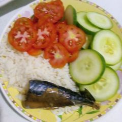 A picture of White rice with sliced cucumbers and 🍅 with fish.
