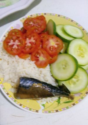 A picture of White rice with sliced cucumbers and 🍅 with fish.