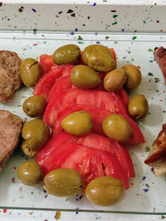 Una foto de Barbacoa de costillas y churrasco ibéricos con tomate y aceitunas