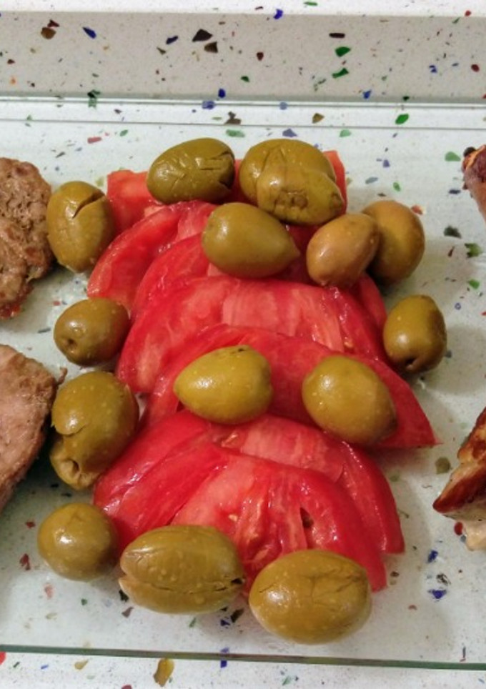 Una foto de Barbacoa de costillas y churrasco ibéricos con tomate y aceitunas