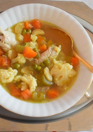 A picture of Chicken and vegetable soup with semolina dumplings.