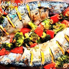 A picture of Mackerel in sour cream, with broccoli and tomatoes, in the oven.