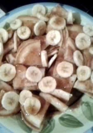 A picture of Pancakes topped w/ bananas and hot cinnamon syrup..