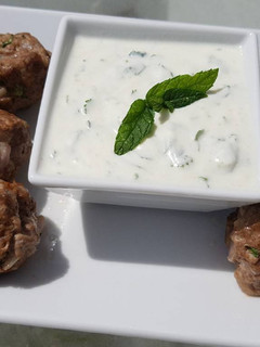 A picture of Spicy lamb meatballs with a tangy yoghurt sauce.
