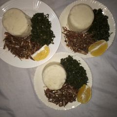 A picture of Ugali,Omena and Greens,Served with an Orange fruit.