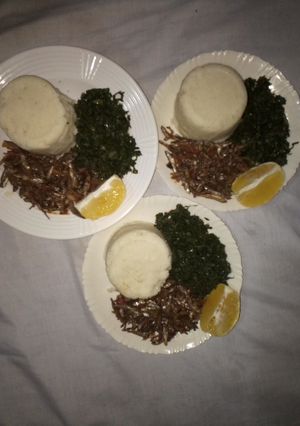 A picture of Ugali,Omena and Greens,Served with an Orange fruit.