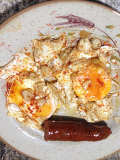 Una foto de Huevos fritos con tocino de jamón, ajos y chorizo picante