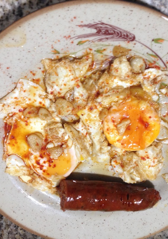 Una foto de Huevos fritos con tocino de jamón, ajos y chorizo picante
