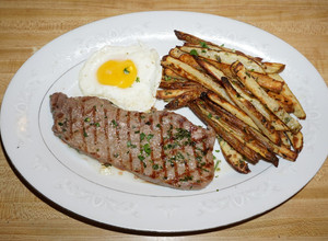Una foto de BISTEC CON HUEVO FRITO Y PAPAS HORNEADAS CON CHAQUETA. JON STYLE