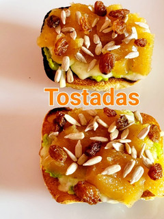 Una foto de Tostas con aguacate, queso, membrillo, pasas y pipas