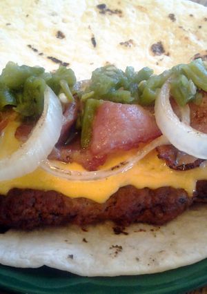 A picture of green chili bacon and cheese tortilla burger.