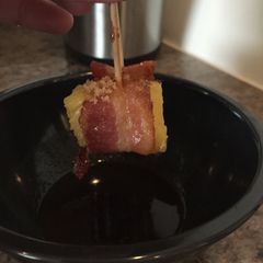 A picture of Candied Bacon-Wrapped Pineapple With Honey Sriracha Sauce.