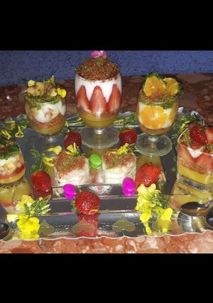 A picture of Kunafa and Qashtalia Decorated with Oranges, Strawberries, and Bananas.