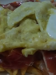 Una foto de Huevos rotos con patatas y jamón