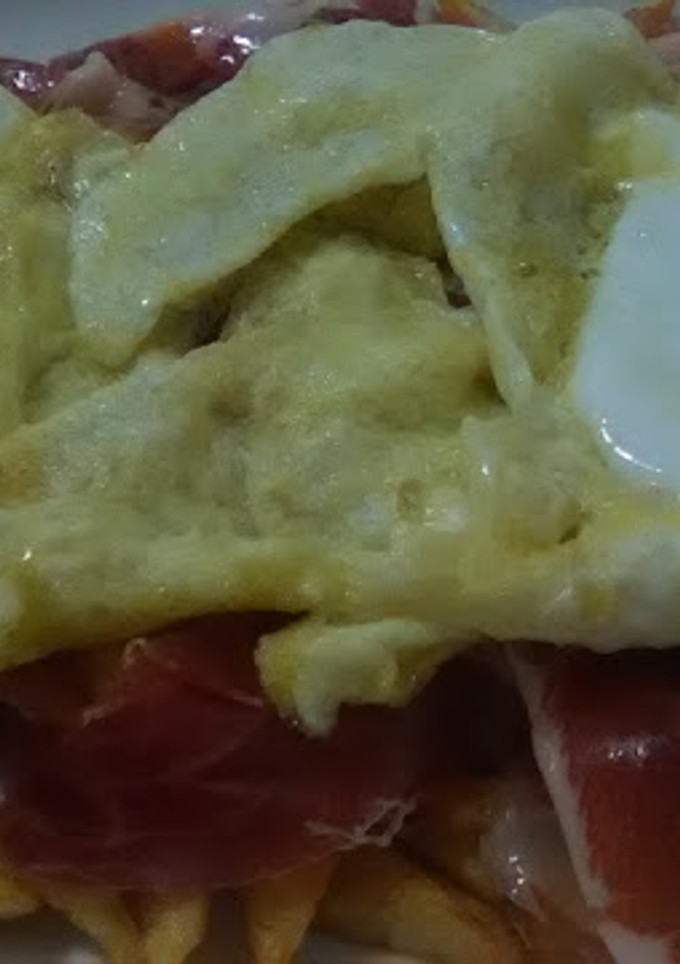 Una foto de Huevos rotos con patatas y jamón