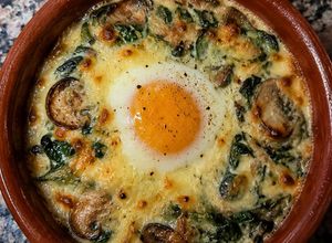 Una foto de Cazuelita Gratinada de Espinaca, Champiñones y Queso con Huevo al Horno 🥚🧀🍄