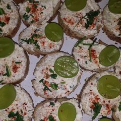 A picture of Bruschette with cheese and grapes.