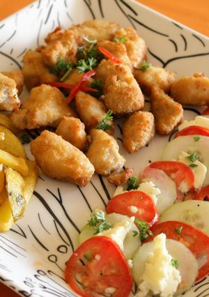 Una foto de Chicharrón de pollo con ensalada de tomate y pepinillo