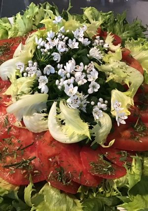 Une photo de Salade reine des glaces aux tomates roses, oignons nouveaux et fleurs d'ail du jardin