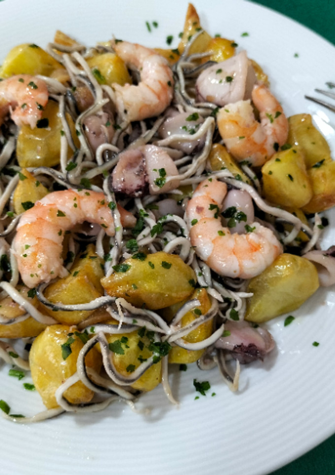 Una foto de Salteado de patatas con calamar, langostinos y gulas al ajillo