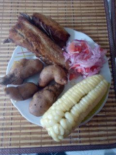 Una foto de Pescado frito acompañado con salsa y choclo papa