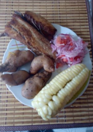 Una foto de Pescado frito acompañado con salsa y choclo papa
