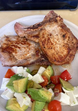 Una foto de Chuleta de cerdo con aguacate, tomate y queso