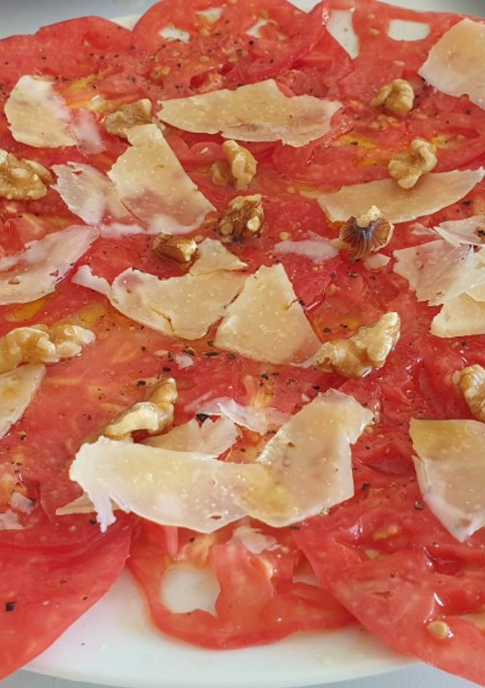 Una foto de Carpaccio de tomate con lascas de queso ahumado y nueces