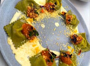 Una foto de Ravioles de albahaca con relleno de queso crema, pepperoni y pistachos en salsa de queso parmesano