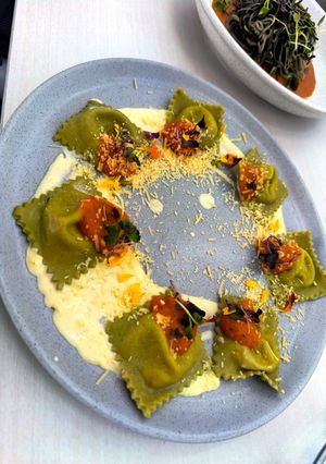 Una foto de Ravioles de albahaca con relleno de queso crema, pepperoni y pistachos en salsa de queso parmesano