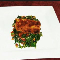 A picture of Grilled breaded Fish filet on a bed of Blanched Spinach.