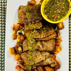 A picture of Beef steak with chimichuri sauce and stir fried apple and vegetables.