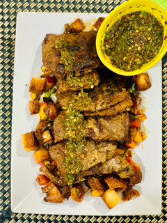 A picture of Beef steak with chimichuri sauce and stir fried apple and vegetables.