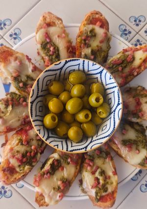 Una foto de Crostini caliente de queso, pesto y jamón