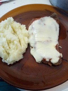 Una foto de Milanesa a la napolitana con puré de papas