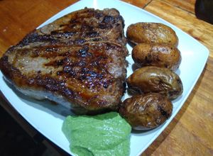 Una foto de T-bone con papines picantes y ajillo de apio