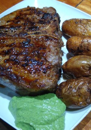 Una foto de T-bone con papines picantes y ajillo de apio