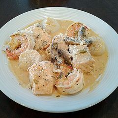 A picture of Salmon, Shrimp and Scallops poached in a Tomato Cream Broth.